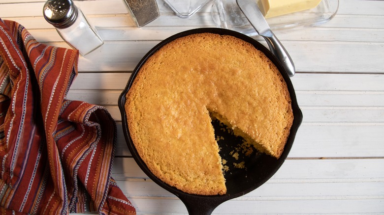 Cornbread in cast-iron skillet top view on white wood table