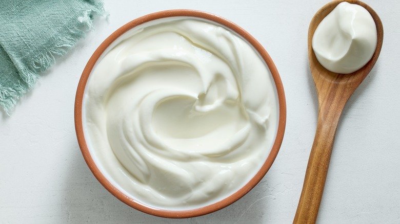 bowl of sour cream on white kitchen table, top view