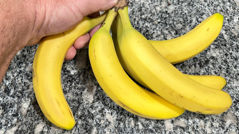 Hand holding a banana sitting on a granite countertop