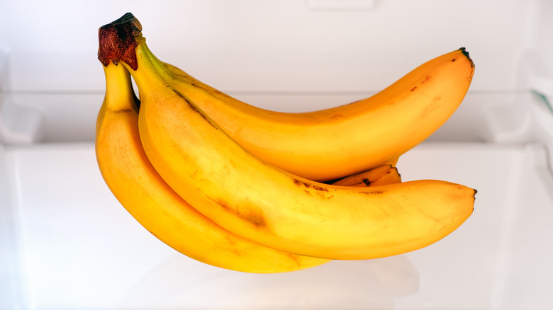A bunch of bananas on the shelf of a fridge