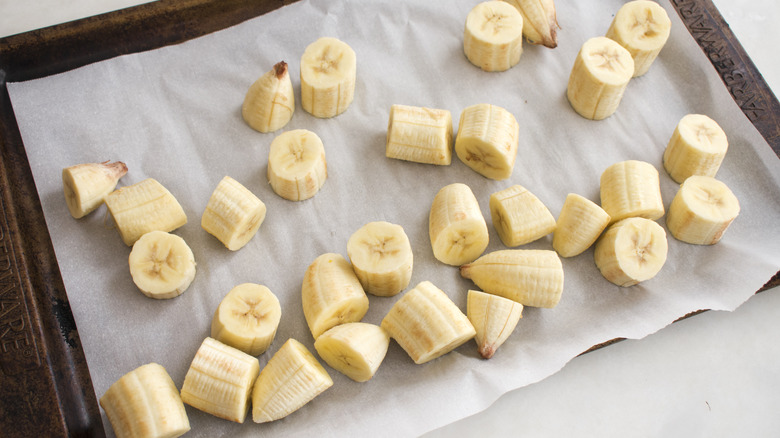 Slices of frozen banana on a parchment-lined sheet pan