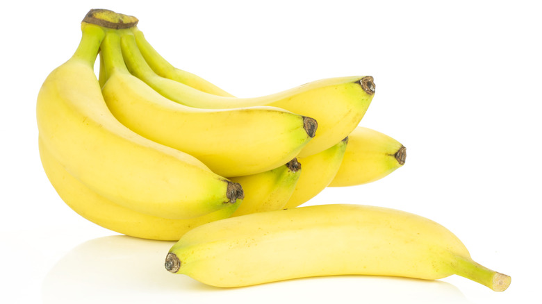 A bunch of bananas and a separate one on a white background