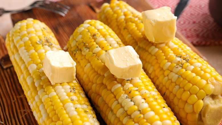 Close-up of corn cobs with large pats of butter on them