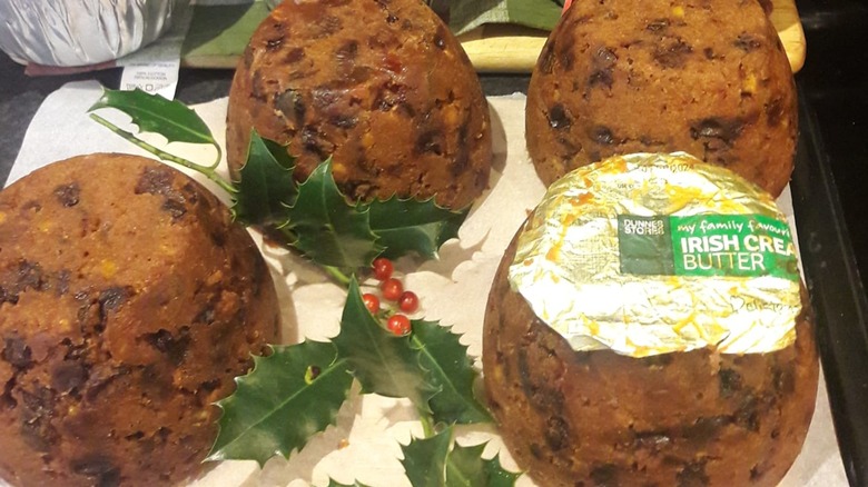 Several steamed Christmas puddings, one covered with a butter wrapper