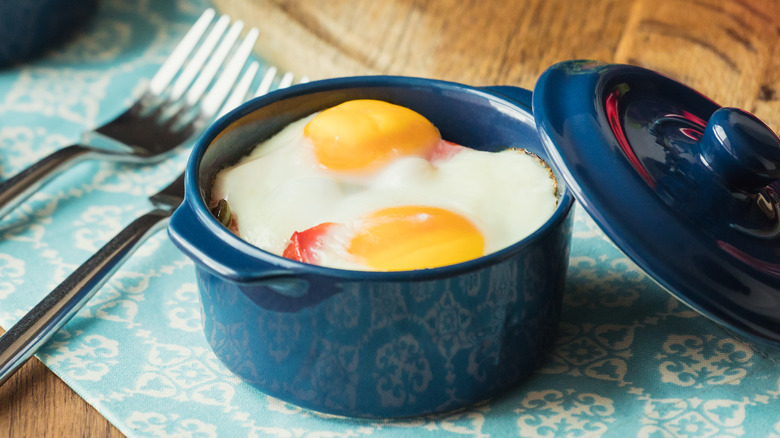 Shirred eggs in a blue pot with a lid