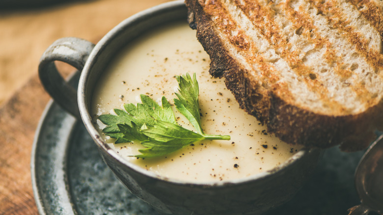 A cup of celery cream soup with toast