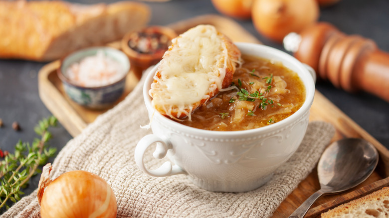 A bowl of onion soup, served with cheese-topped bread