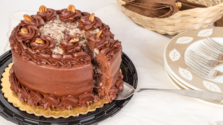 german chocolate cake on cake board with serving plates nearby.