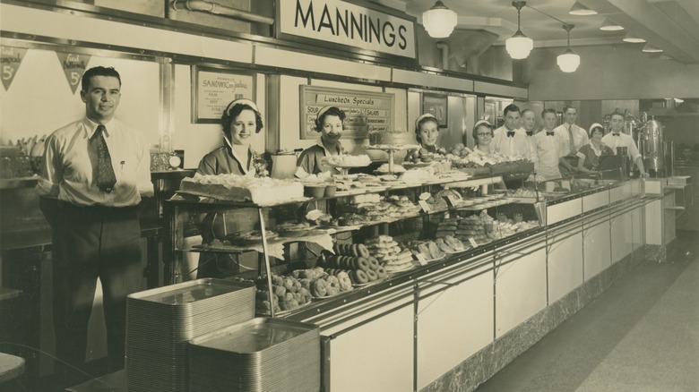 bakery staff stand near an assortment of treats on display