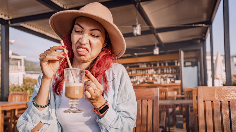 Woman making disgusted face at outdoor coffee bar