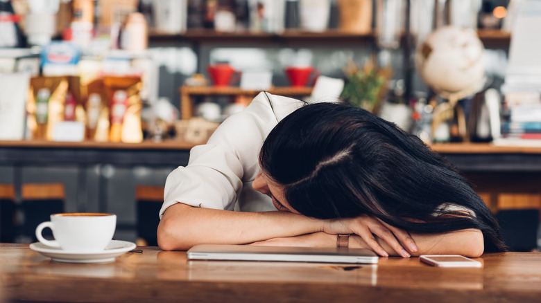 Woman resting her head on table in coffee shop