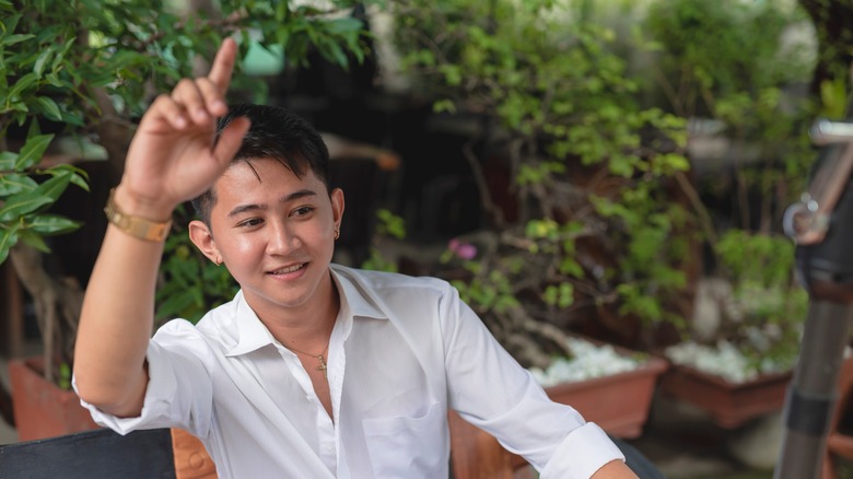 A man raises his hand to get waiter's attention at outside restaurant