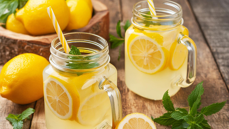 Homemade lemonade with lemon and mint in mason jar on wooden table.