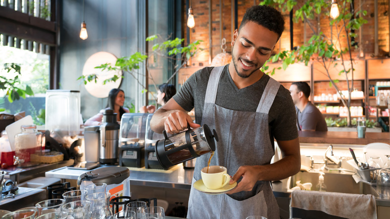 Barista making coffee behind bar