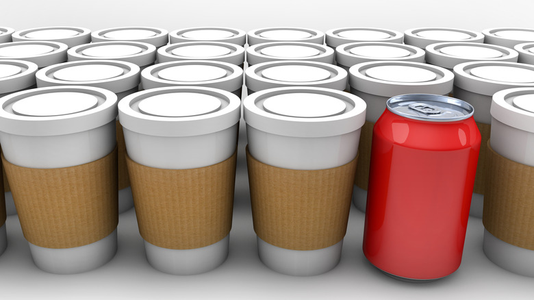 A line of coffee cups with a single red soda can among them