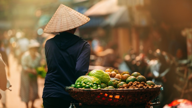 vietnamese woman walks with cart of fruits and veggies
