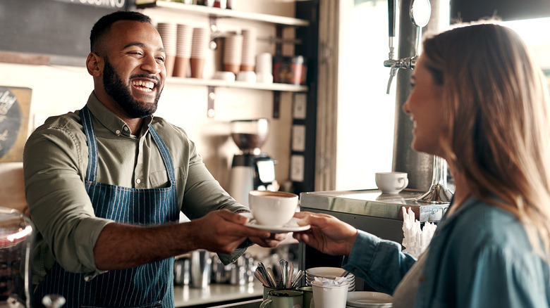 barista passing coffee to woman