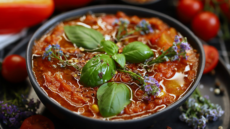 A bowl of tomato soup topped with fresh basil