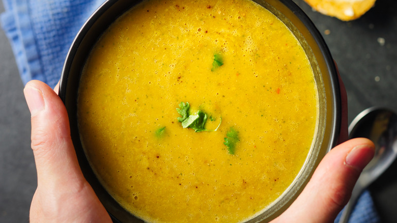 Cloe up of someone holding a bowl of butternut soup