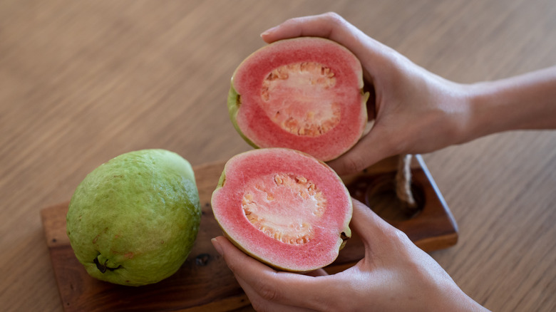 Someone holding two halves of a guava