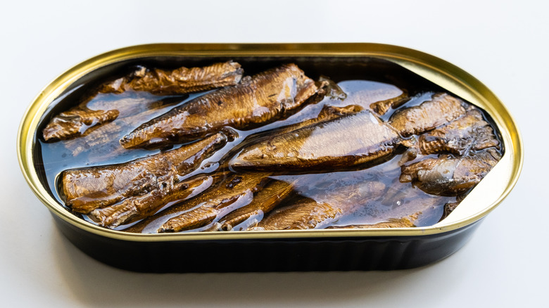 Sprats with oil in the open tin can on the white background