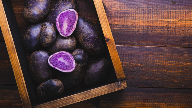 purple potatoes in wooden box on wooden table