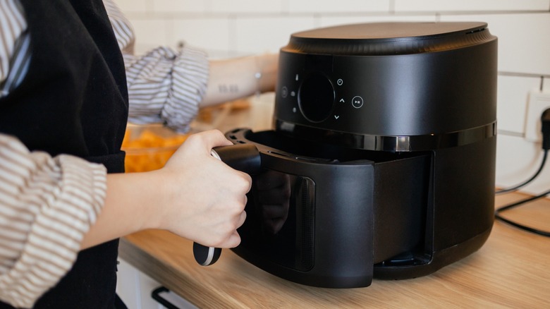 a hand closes an air fryer basket