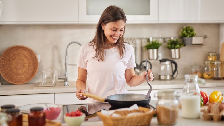 woman cooks food in a frying pan