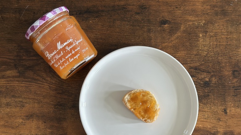 Jar of Bonne Maman Apricot Spread beside white plate with baguette slice