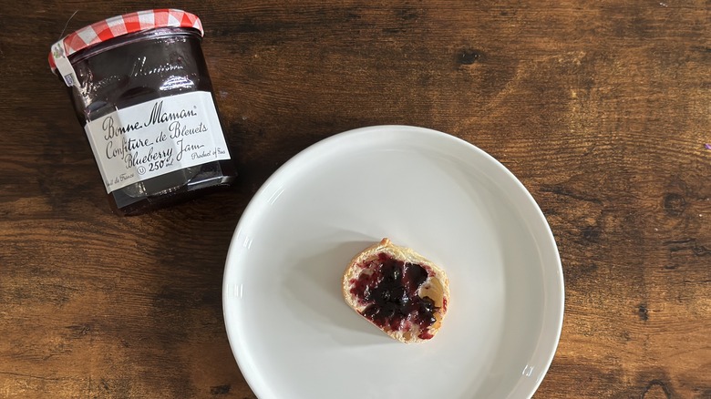 Jar of Bonne Maman Blueberry Jam beside white plate with baguette slice