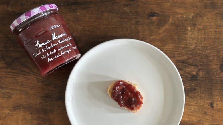 Jar of Bonne Maman Raspberry Spread beside white plate with baguette slice