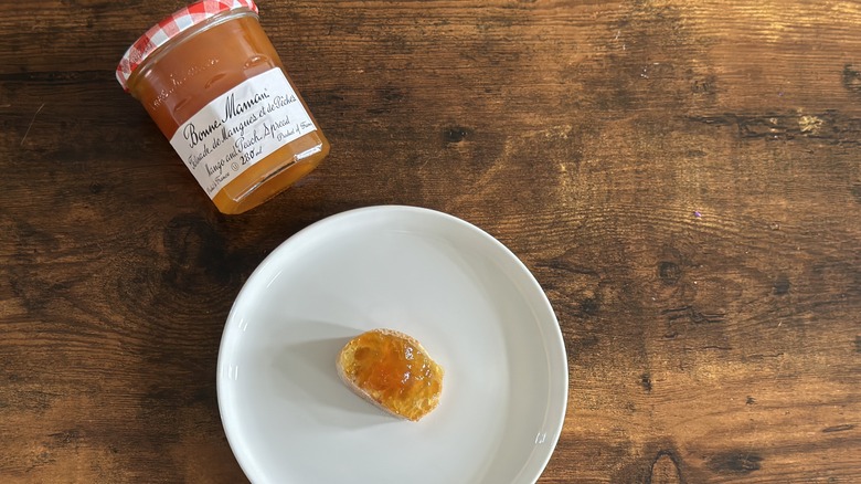 Jar of Bonne Maman Mango and Peach Spread beside white plate with baguette slice
