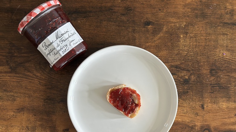 Jar of Bonne Maman Raspberry Jam beside white plate with baguette slice