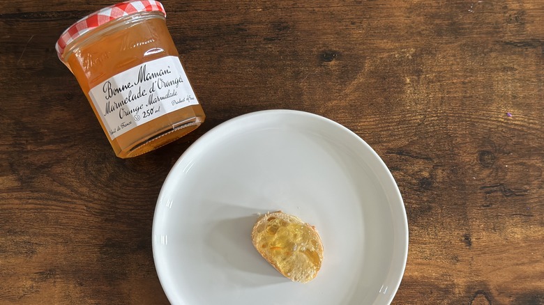 Jar of Bonne Maman Orange Marmalade beside white plate with baguette slice