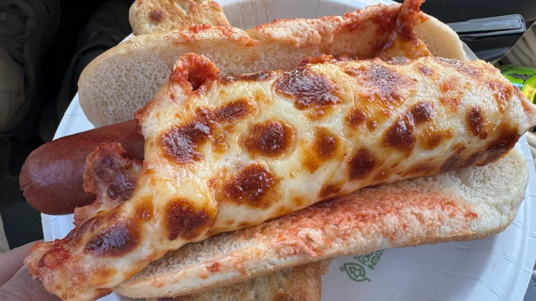 Hot dog wrapped in pizza cheese on paper plate