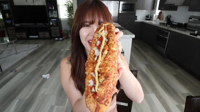 woman holding up a Costco Jochizza to camera