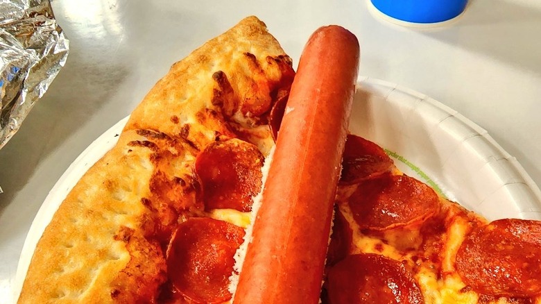 Costco hot dog laid across slice of pizza