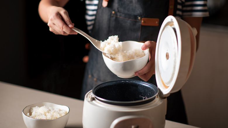 Person taking rice from rice cooker