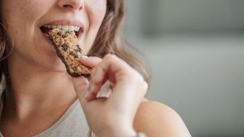 woman eats a granola bar with chocolate chips