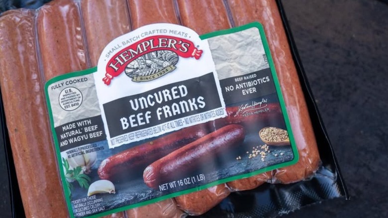 Hand holding a package of Hempler's hot dogs
