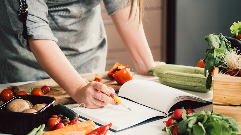 woman writing notes while cooking
