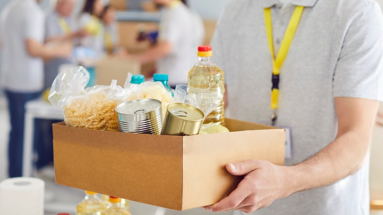 Food bank volunteer holds out a box of donated foods