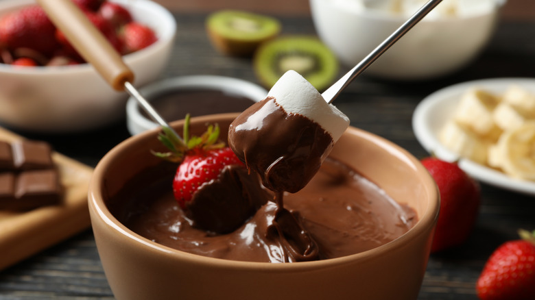 Marshmallow and strawberry dipping into chocolate fondue