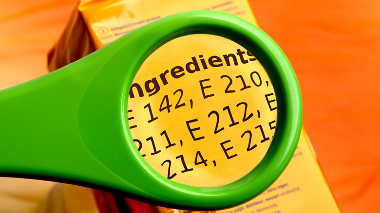 A vivid green magnifying glass held over the ingredients list on a bright yellow box