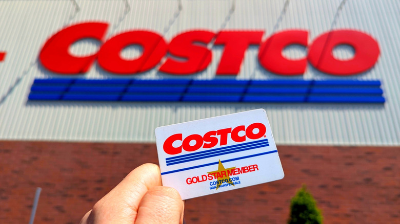 Costco Wholesale Gold Star Membership Card Held In Hand in Front of Storefront Location