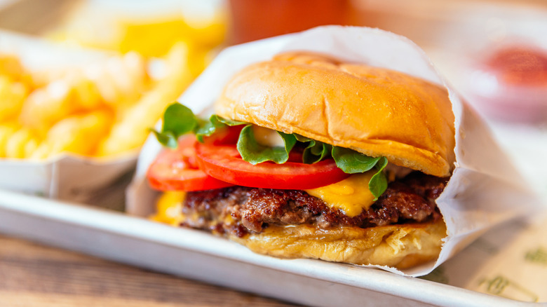 Image of a juicy burger with cheese, lettuce, and tomatoes