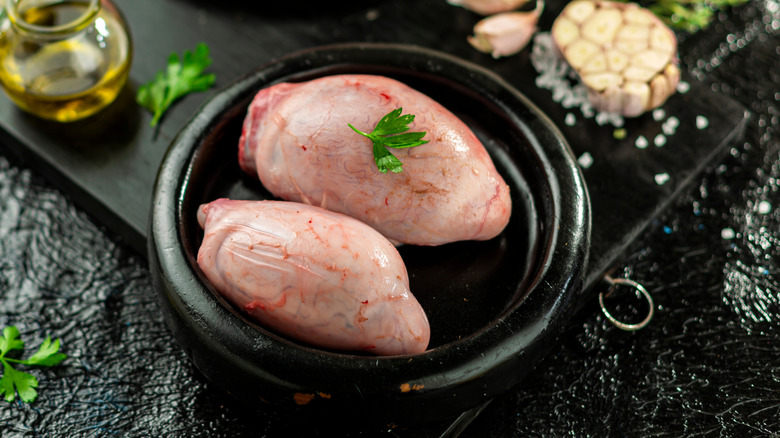 Two veal testicles in a black bowl