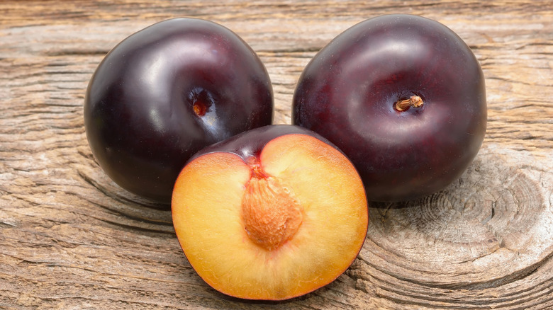 Two hole, ripe black plums, with one halved