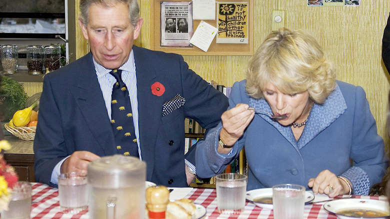 Prince Charles and Camilla eating soup at a table