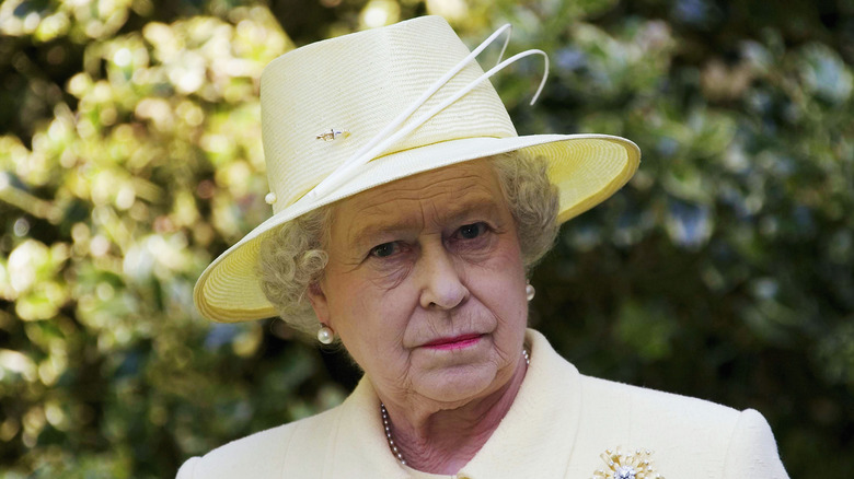 Queen Elizabeth in a yellow hat looking straight to camera